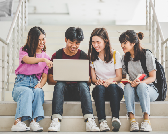 Students sitting on stairs looking at a laptop